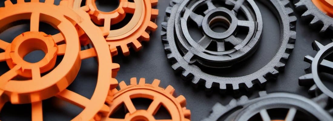 Engranajes impresos en 3D en PLA naranja y gris, engranados entre sí